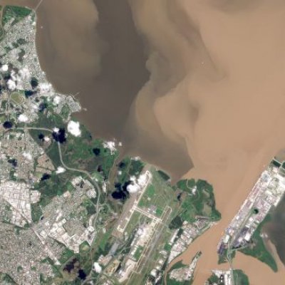 an aerial image of suburbs and a river with brown water coming out of it